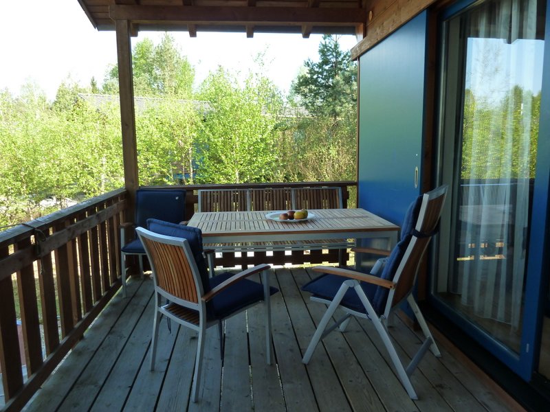 Eine große, überdachte Terrasse mit Blick über den See ist vom Wohnraum aus begehbar.